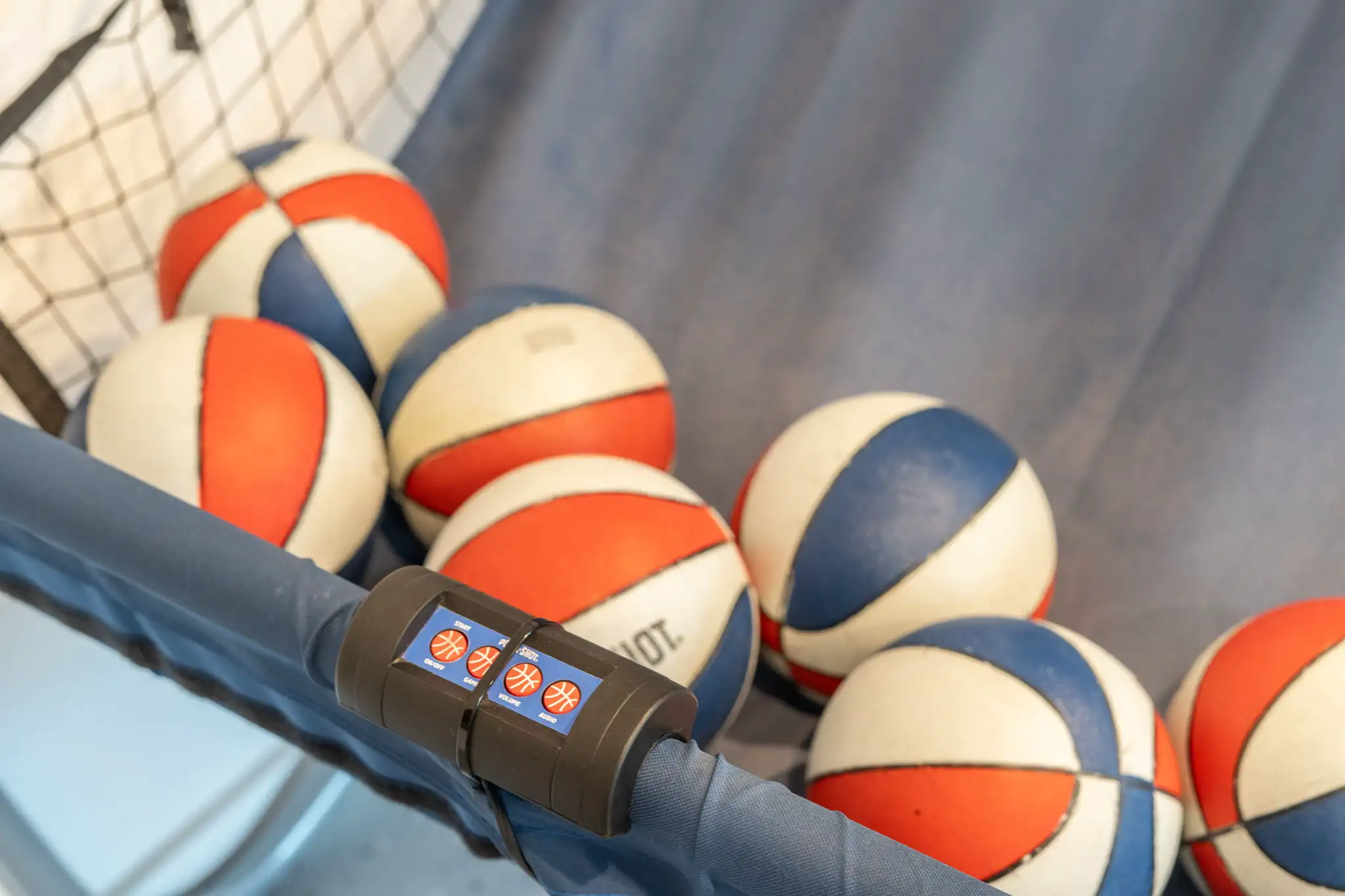 Close-up of an arcade basketball game showing many small red, white, and blue balls and a digital control panel.